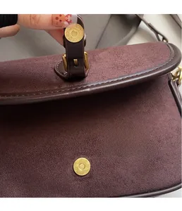 Detail view of burgundy frosted suede bag with vintage gold magnetic buckle closure