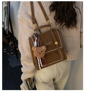 Detail of vintage brown leather backpack with contrast stitching and teddy bear charm