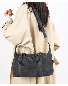 Detailed side view of a grey vintage tote bag worn by a model in a trench coat