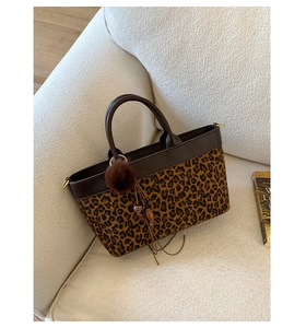 Dettaglio della borsa leopardata con manici in pelle marrone e ciondolo di peluche