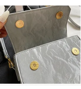 Detail view of the silver crinkled handbag with four magnetic gold snap closures