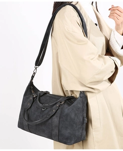 Detail of black matte Boston tote bag with metal triangle logo and adjustable strap