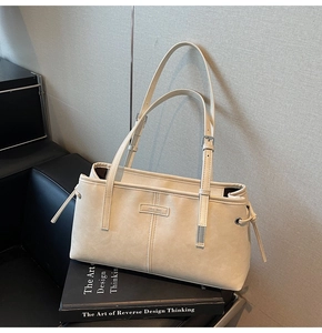 Detailed view of cream leather shoulder bag featuring adjustable strap and side drawstrings