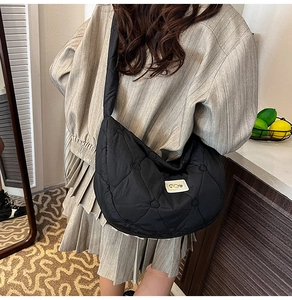 Close-up of black quilted puffer bag with heart-shaped stitching and S.O.Y brand label