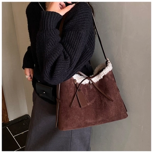 Detail of suede shoulder bag with white faux fur trim and adjustable drawstring closure