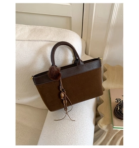 Borsa tote in pelle scamosciata marrone scuro con finiture in pelle e nappa su divano