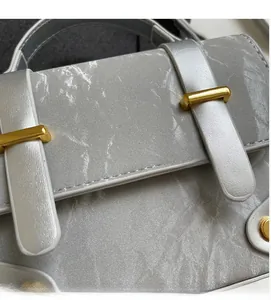 Detail of grey crossbody bag featuring marble texture PU leather and gold metal clasp