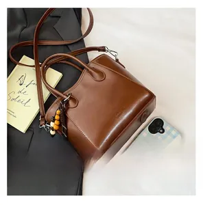 Détail d'un sac seau marron en similicuir avec breloque en perles sur un blazer noir