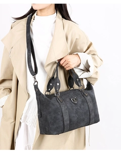 Detailed view of grey vintage tote bag with metal shield logo on beige coat model