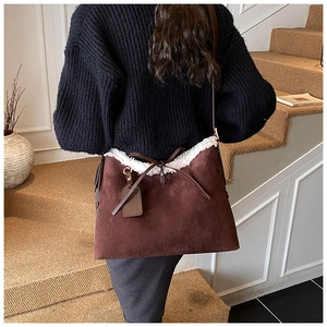 Detail of suede shoulder bag featuring white faux fur trim and delicate bow detail