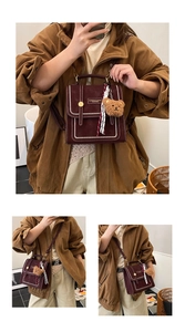 Detail of burgundy vintage backpack with white stitching and plush bear charm