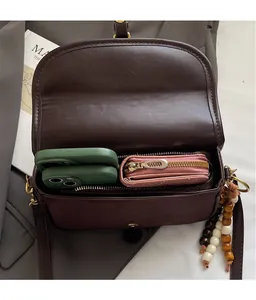 Top view of brown matte leather bag showing spacious interior with phones and beaded tassel
