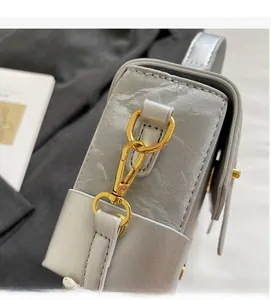 Detail of silver handbag with pleated texture and high-gloss gold metal hardware hooks