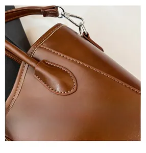 Vue macro d'un sac seau en cuir marron caramel montrant les coutures fines et les boucles