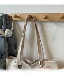 Detail of canvas tote bag with cat embroidery and decorative charms on a wall hook
