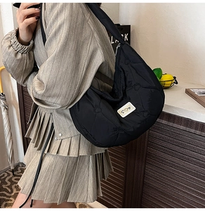 Detailed view of black quilted heart crossbody bag with white brand label on nylon
