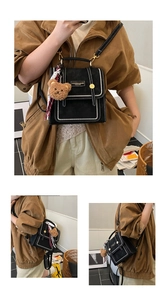 Detail of vintage black mini backpack with white stitching and plush bear charm