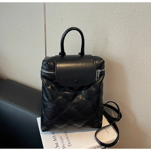 Close-up of black quilted leather backpack with embossed floral pattern and zipper