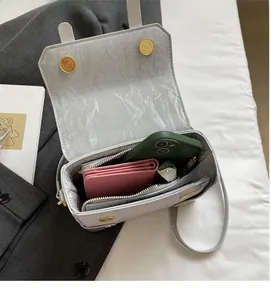 Detail view of light grey leather shoulder bag showing spacious interior with magnet closure