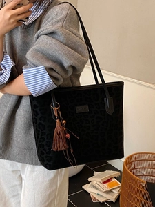 Chic black leopard print tote bag with brown tassel and beads in a lifestyle setting