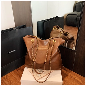 Detailed macro view of brown leather bucket bag with gold chain strap and metal eyelets