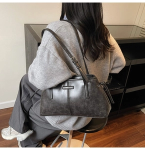 Close-up of matte vintage leather bag with drawstring side detail and adjustable strap