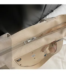 Detailed macro view of the smooth silver metal zipper on the beige canvas tote bag