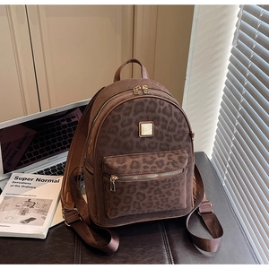 Détail du sac à dos léopard montrant la texture en daim et les fermetures éclair dorées