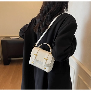 Vue détaillée du petit sac bandoulière en cuir blanc cassé avec boucles dorées sur noir