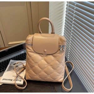 Detail of beige quilted leather backpack with floral stitching and metal zipper
