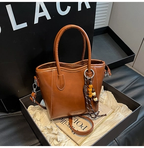 Détail du sac seau marron rétro avec breloque à perles et bandoulière amovible