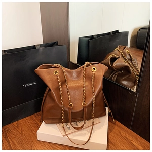 Detailed view of dark brown leather bucket bag with golden chain straps and glossy finish