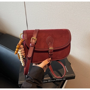 Detailed close-up of retro burgundy crossbody bag with matte texture and beaded tassel