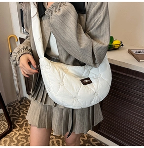 Detail of white quilted crescent bag with heart embroidery and pearl logo detail