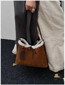 Detail of brown suede shoulder bag with white faux fur trim and leather tie decoration