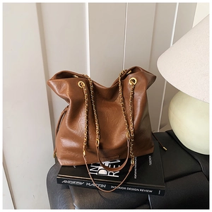 Brown bucket bag detail with chain straps and drawstring on leather tote bag