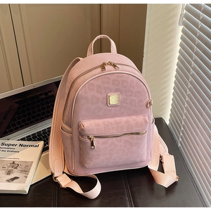 Détail du sac à dos rose à motif léopard avec fermetures éclair dorées et plaque métal