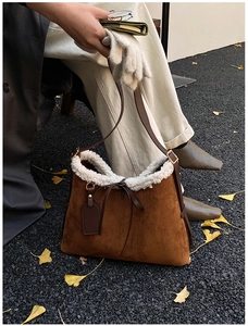 Brown suede shoulder bag with white faux fur trim and bow detail in autumn setting