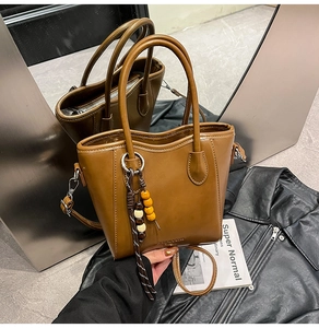 Détail d'un sac seau marron avec breloque perlée et logo Fashion & Bags gaufré chic