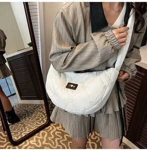 Detail of white puffer crescent bag featuring heart quilted stitching and leather logo patch