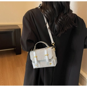Détail du mini sac carré en cuir argenté texturé avec des finitions dorées chic