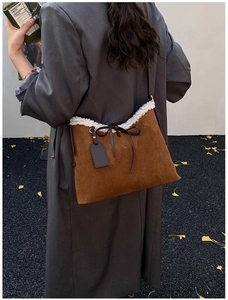 Detail of dark brown suede shoulder bag with white faux fur trim and leather bow detail