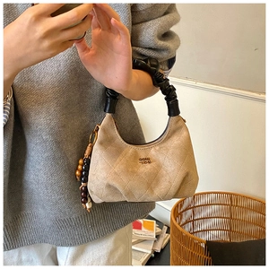 Detail of quilted hobo dumpling bag with black scrunchie handle and wooden bead charms
