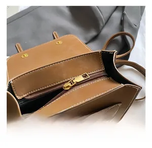 Detail of brown leather backpack featuring gold hardware and interior zipper pockets