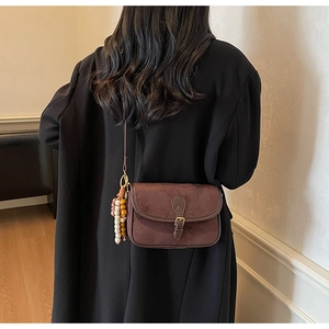 Detail of vintage brown suede crossbody bag with decorative beads on a black coat
