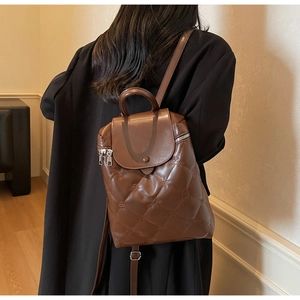 Brown quilted leather backpack with rhombus stitching shown on a model's shoulder