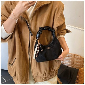 Quilted black suede crescent bag with ruffled handle and bead charm on model