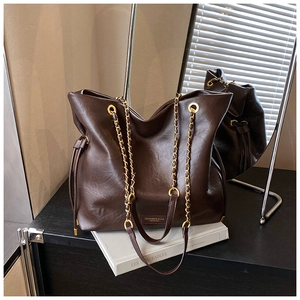 Detail of deep brown faux leather tote bag with elegant chain strap and metal nameplate