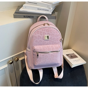 Gros plan du sac à dos léopard rose avec fermeture éclair dorée et texture cuir synthétique