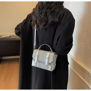 Détail du sac bandoulière plissé gris argenté avec poignée métallique et boucle dorée